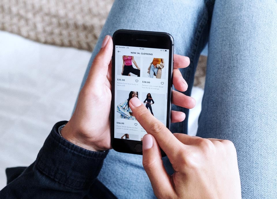 Någon som scrollar inne på en hemsida som säljer kläder på sin mobil